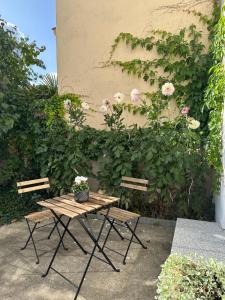 una mesa de picnic y dos sillas junto a una pared con flores en Mittendrin en Cottbus
