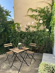 a picnic table and two chairs next to a wall with flowers at Mittendrin in Cottbus