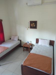 a room with two beds and a table at Hotel Tentrem Syariah in Probolinggo