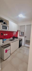 a kitchen with white cabinets and a red wall at Amma Selva Temporarios in Posadas
