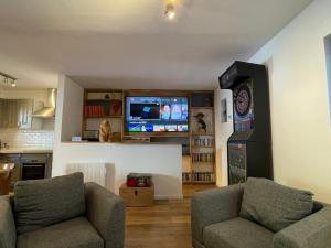 a living room with two chairs and a flat screen tv at maison colmars in Colmars
