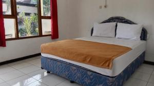 un grande letto in una stanza con due finestre di Hotel Tentrem Syariah a Probolinggo
