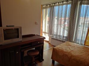 a room with a television and a desk with a bed at Къща за гости M-Stone in Bansko