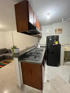 ブカラマンガにあるHABITACION BAÑO PRIVADO - EXCELENTE UBICACIONのキッチン(コンロ、黒い冷蔵庫付)