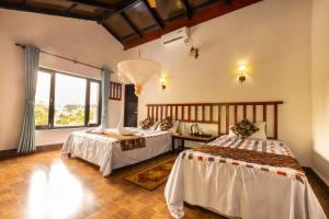 una camera con due letti e una grande finestra di Hotel Parkside & Swimming Pool-Between Greenery and Azure ,Your Perfect Retreat a Chitwan Altre 37 foto