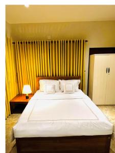 una camera da letto con un grande letto bianco con tende gialle di Ceylon Kingsmen Garden Hotel - Katunayake a Negombo