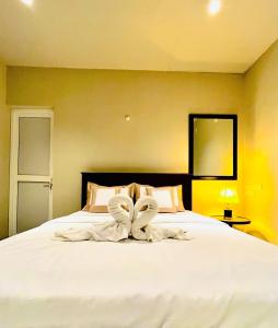 een slaapkamer met een groot bed met witte lakens bij Ceylon Kingsmen Garden Hotel - Katunayake in Negombo