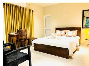 a bedroom with a large bed and yellow curtains at Ceylon Kingsmen Garden Hotel - Katunayake in Negombo