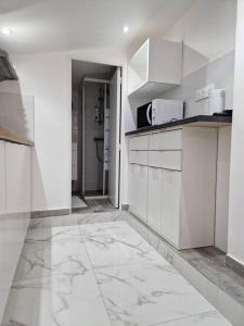 a kitchen with white cabinets and a tile floor at StudioNeuf équipé CDG/Parc Expo/ Paris in Aulnay-sous-Bois