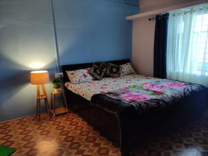 a bedroom with a bed and a lamp and a window at The Heavens in Almora