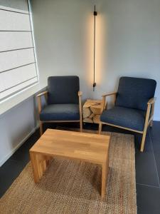two chairs and a coffee table in a room at Gîte de la Côte Dor : logement zen à la campagne in Fosses-La-Ville