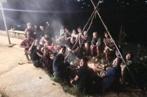un grupo de personas sentadas alrededor de un fuego por la noche en Vietoutdoors Homestay, en Sa Pa