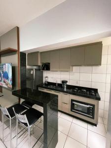 une cuisine avec un comptoir, une cuisinière et des chaises dans l'établissement Condomínio Colina, à Palmas
