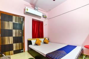 SPOT ON Hotel Vivek في Hājīpur: غرفة صغيرة مع سرير ووسائد ملونة