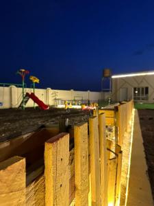 a wooden fence in front of a playground at night at استراحة السهيلي بديه in Al Ghabbī