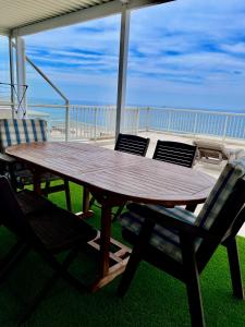 a wooden table and chairs on a porch with the beach at 101 Camarque - Beachfront Apartment in Umdloti