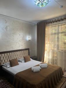 a bedroom with a large bed with a large window at Hotel Al-Bukhory in Samarkand