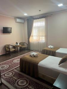 um quarto de hotel com duas camas e uma mesa em Hotel Al-Bukhory em Samarcanda