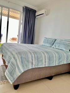 a bedroom with a bed with a blue and white comforter at 101 Camarque - Beachfront Apartment in Umdloti