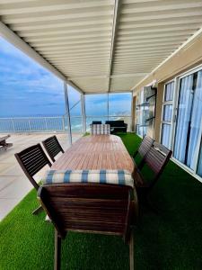 a table and chairs on a patio with a view of the ocean at 101 Camarque - Beachfront Apartment in Umdloti