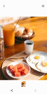 una mesa con desayuno de huevos, fruta y zumo en IGUANA HOUSE en Máncora