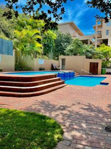 a house with a swimming pool and stairs in a yard at 101 Camarque - Beachfront Apartment in Umdloti