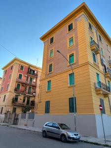 un edificio amarillo con un coche aparcado delante de él en Altopiano Rooms en Foggia