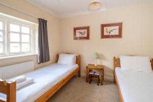 two twin beds in a room with a window at Salt Cellar Cottage in Aldeburgh
