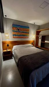 1 dormitorio con 1 cama y una pintura en la pared en Casa Oceano Praia do Rosa, apartamentos pé na areia, Praia do Rosa, en Praia do Rosa
