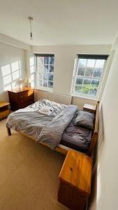a bedroom with a bed and a table and two windows at Traditional 3 Bed Flat In Highgate in London