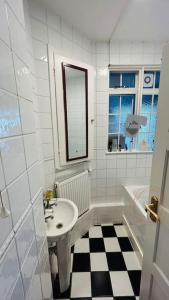 Baño blanco con lavabo y espejo en Traditional 3 Bed Flat In Highgate en Londres