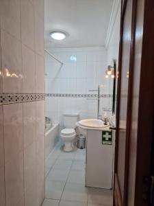 a white bathroom with a toilet and a sink at Furadouro - Apartamento Praia in Ovar