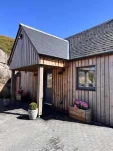 een houten gebouw met een deur en wat bloemen bij Raasay Studio Lodge in Arisaig