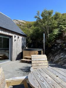 a wooden deck with two chairs and a table at Raasay Studio Lodge in Arisaig