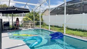 a woman is standing next to a swimming pool with an inflatable at Renovated Entire House Heated Pool Close 2 Disney in Kissimmee