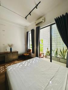 - une chambre avec un lit blanc et une grande fenêtre dans l'établissement Loka Home & Yoga, à Đà Nẵng