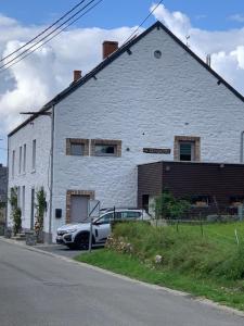 Un bâtiment blanc avec une voiture garée devant. dans l'établissement Ca’Benvenuto, à Doische