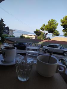 a table with cups and glasses on a balcony with a car at Hotel Chicago in Sarandë