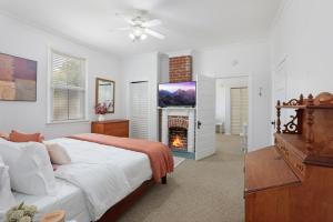 a white bedroom with a bed and a fireplace at Redstick Cottage in Baton Rouge