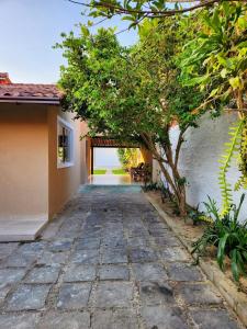 a stone pathway leading to a house with a tree at Bela casa de praia sossegada no Centro de Búzios in Búzios