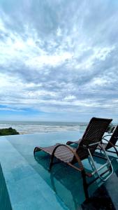 una silla sentada en el borde de una piscina en Casa Oceano Praia do Rosa, apartamentos pé na areia, Praia do Rosa, en Praia do Rosa