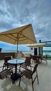 a patio with tables and chairs and an umbrella at Casa Oceano Praia do Rosa, apartamentos pé na areia, Praia do Rosa in Praia do Rosa