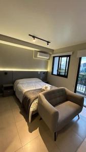 ein Schlafzimmer mit einem Bett, einem Sofa und Fenstern in der Unterkunft Studio Moema ao lado do Shopping e metro in São Paulo