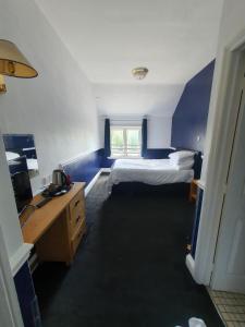 Ein kleines Zimmer mit einem Bett und einem Schreibtisch sowie einem Bett sidx sidx sidx sidx sidx. in der Unterkunft Regency Hotel in Leicester