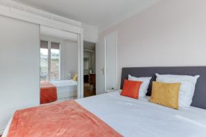 a bedroom with a bed with orange and white pillows at Countryside in Paris 14 - Lovely and Calm 1bd Flat in Paris