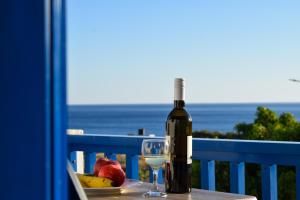 a bottle of wine and a glass on a table with fruit at Katovigli Seaview Apartment in Makry Gialos
