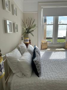 Un dormitorio con una cama con almohadas blancas y una ventana en Beautiful Elie Beach house,South St with Sea view, en Elie