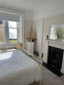 a white bedroom with a bed and a fireplace at Beautiful Elie Beach house,South St with Sea view in Elie