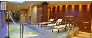 una piscina con sillas y una bañera de hidromasaje. en Apartamento en Urbanización de lujo con piscina, gimnasio y spa Aparcamiento GRATIS en la zona, en Córdoba
