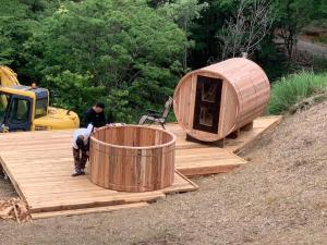 Ein Mann, der eine Holzbadewanne auf einem Deck baut in der Unterkunft Starry Sky and Sea of Clouds Hotel Terrace Resort - Vacation STAY 75154v in Takeda